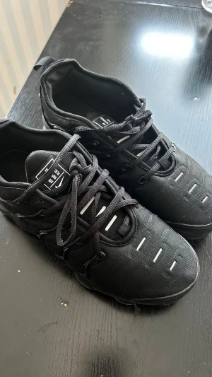 Svarta sneakers från Vm Aim - Svarta sneakers med sportig design från Vm Aim. Skorna har svarta snören, diskreta vita detaljer på ovandelen och en robust sula. Tillverkade i textil och syntetmaterial för en modern look. Perfekta för dig som gillar stilrena och bekväma sneakers.