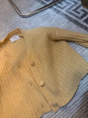 Gul ribbstickad tröja från Zara - Snygg gul ribbstickad tröja från Zara med rund halsringning och långa ärmar. Tröjan har en smal passform och är perfekt för lager-på-lager. Materialet känns mjukt och bekvämt mot huden.