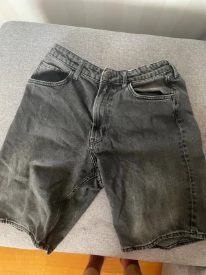 Svarta denimshorts  - H&M - Klassiska svarta jeansshorts i denim med fem fickor och normal passform. Shortsen har en knapp och dragkedja framtill samt bälteshällor. Märke: H&M 