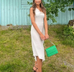 Vit oneshoulder klänning - Säljer en elegant vit långklänning med oneshoulder-design och asymmetrisk fåll. Klänningen har en figurnära passform och är tillverkad i ett lätt, mjukt material som ger ett stilrent intryck. Perfekt för dig som vill ha en enkel men snygg look.
