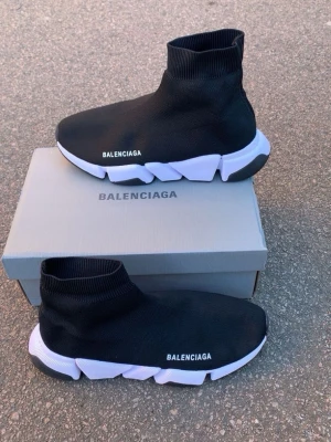 Balenciaga Speed Trainer svarta sneakers - Svarta Balenciaga Speed Trainer sneakers med vit chunky sula och stickad ovandel i textil. Strumpliknande passform och logga på sidan. Snygg och futuristisk design som sticker ut. Perfekta för dig som gillar streetwear och vill ha något unikt.