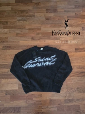 Svart stickad Saint Laurent tröja - 🖤 Saint Laurent Logo Sweater – Svart | Strl M 🖤 Stilren och exklusiv Saint Laurent-tröja i svart med ikonisk vit logotyp framtill. Tillverkad i mjukt material med lyxig känsla och bekväm passform. Tagg avklippt. En tidlös modell som passar både till vardags och mer uppklädda outfits. Tröjan är i nyskick, helt oanvänd. Made in Italy. 📦 Snabb leverans – skickas samma dag (om ej hindr.).