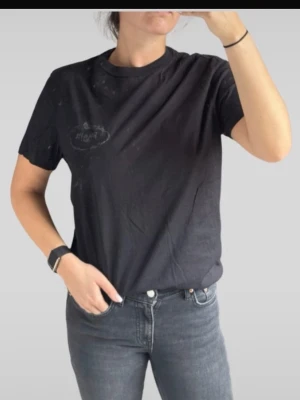 Prada T-shirt - Svart t-shirt från Market med diskret logga på bröstet. Klassisk rund halsringning och korta ärmar. Tillverkad i mjuk bomull som känns skön mot huden. Perfekt för en avslappnad och stilren look.