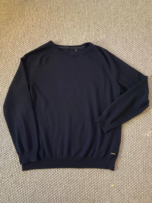 Hugo Boss Stickad Tröja - Säljer en stilren och tidlös mörkblå stickad tröja från Hugo Boss. Tröjan har en klassisk design med rund hals och en diskret metallogo längst ner som ger en exklusiv känsla. Den är mjuk, bekväm och perfekt att bära under de kallare månaderna – lika snygg till vardags som till en mer uppklädd outfit.  • Märke: Hugo Boss • Storlek: XL • Färg: Mörkblå • Skick: Bra skick  En riktigt fin baströja som passar till det mesta. Rökfritt hem❌🚬  Skriv om du har frågor eller vill ha fler bilder! //Arvid
