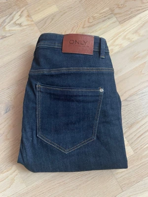 Mörkblå bootcut jeans från ONLY - Snygga mörkblå jeans från ONLY med bootcut passform och klassiska fem fickor. Jeansen har hög midja och är tillverkade i ett mjukt denimtyg med stretch. 