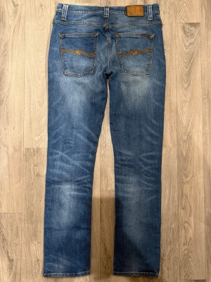 Nudie Jeans Grim Tim Used Indigo Blå W31/L32 - Mycket fint skick. Storlek W31/L32. Mått: Midja: 40,5cm, Ytterbenslängd: 105cm, Benöppning: 17,5cm. Modellen är 185cm & 65kg. Hör av dig vid funderingar!🤝
