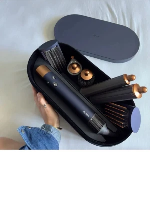 Dyson Airwrap multistyler med tillbehör - Säljer en Dyson Airwrap multistyler i mörkblå och kopparfärg med flera stylingtillbehör. Setet innehåller olika borstar och cylindrar för att skapa lockar, volym och släta frisyrer. Allt levereras i ett snyggt, hårt fodral. Perfekt för dig som vill ha proffsigt hår hemma. KÖPT förra året från lyko men knappt använd då den inte passade min hårtyp 