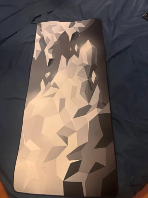 Xtrfy stor musmatta med mönster - Säljer en stor musmatta från Xtrfy med ett snyggt geometriskt mönster i grå, svart och vit. Mattan har rektangulär form och sydda kanter för extra hållbarhet. Perfekt för gaming eller kontor där du vill ha mycket utrymme för musrörelser.