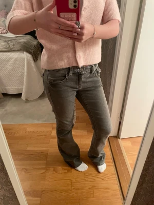 Gråa bootcut jeans från Gina young  - Säljer ett par gråa bootcut low-middle waist jeans från Gina young i storlek 170! Super snygga och jätte skönt tyg med snygg passform, de är använda men är fortfarande i mycket bra skick, har även en justerbar midja med resår💗