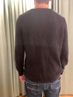 Samsoe samsoe - En enkel och stilren svart stickad tröja med rund halsringning och långa ärmar. Tröjan har en rak passform och ribbade muddar vid ärmslut och nederkant. Perfekt att matcha med jeans för en avslappnad look.