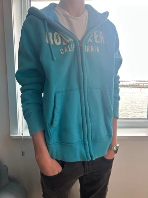 Blå zip vintage hoodie från Hollister - En riktigt fet hollister tröja! Sitter lite för stort på, den sitter som L och har fint skick. Skick:9/10 | modellen är 185cm lång. Pris 599 men kan diskuteras🤩🤩