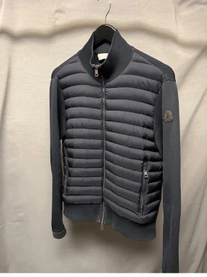 Moncler cardigan M - Säljer denna sjukt feta moncler black label cardigan! Garanterad äkthet. Size M sitter som S. Modellen är 180cm. Skick 8/10 lite slitna muddar annars superfin! Nypris hela 14.000kr! Hör av dig vid minsta fundering 🤩