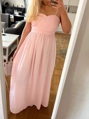 Rosa balklänning  - En superfin rosa balklänning. Den funkar både med och utan band ifall man skulle vilja ta av dom. Storlek S. Midjemått: 77cm. Bystmått: 82cm. Längd:126 cm. Dragkedjans längd: 43cm💕 klänningen är för liten för mig därav att dragkedjan inte är uppdragen helt.