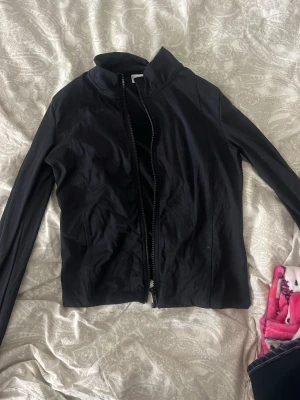 Svart jacka från Gina Tricot - Snygg svart jacka från Gina Tricot med rak passform och dragkedja framtill. Jackan har en enkel, stilren design och är långärmad. Perfekt att slänga på sig till vardags för en clean look.