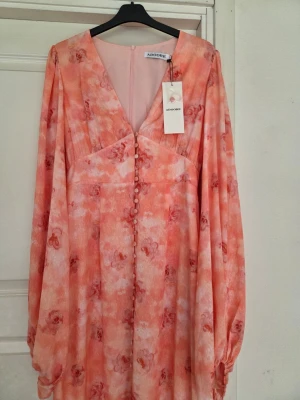 Adore blommig långklänning i rosa - Klänning från Adoore i storlek 38. Helt ny, aldrig använd! Endast testad. Lappar kvar. 1000kr