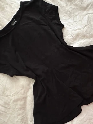 Svart peplum top - En svart peplum top  i mjuk bomull. Klassisk rund halsringning och korta ärmar. Perfekt till jeans eller kjol för en clean och avslappnad look.