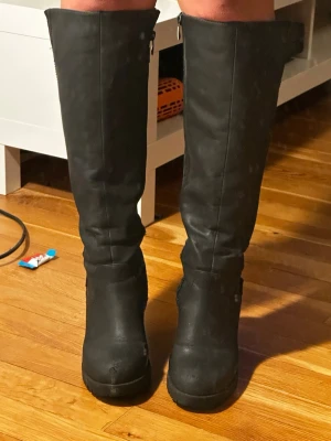 Svarta höga stövlar med klack - Snygga svarta knähöga stövlar med bred klack och rundad tå. Extremt bekväma, man kan inte få ont i fötterna av dessa. Dom är väl använda och slitna därav priset. Men helthetsintrycket är bra