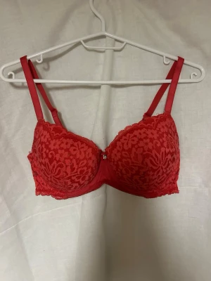 BH från Hünkemöller - Snygg röd bh med vadderade kupor och blommig spets. Används inte längre❤️