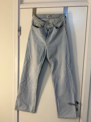 Ljusblå raka jeans från 157 - Säljer ett par ljusblå jeans från 157 med rak passform och hög midja. Jeansen har klassiska fem fickor, bälteshällor och stängs med knapp och dragkedja. Tillverkade i bomull för en skön och avslappnad look.
