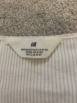 Vit ribbad stickad tröja H&M - Säljer en vit ribbad stickad tröja från H&M med lång ärm och fyrkantig halsringning. Tröjan är mjuk och har en enkel, stilren design som passar perfekt till jeans eller kjol. Perfekt för dig som gillar minimalistisk stil. storlek 146/152🫰🏼❤️