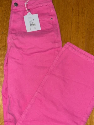 Rosa raka jeans från Bik bok - Snygga rosa jeans från Bik bok med rak passform och klassisk femficksdesign. Jeansen har hög midja och stängs med knapp och dragkedja. Perfekta för dig som vill sticka ut med färg! Materialet är bomull med lite stretch. W. 27 & L.32