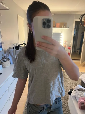 Grå basic t-shirt i bomull - En enkel och stilren grå t-shirt från Gina i storlek M. Modellen är rak med korta ärmar och rund halsringning. Perfekt till jeans eller shorts för en avslappnad look. Skriv om du undrar något💕