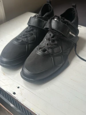 Svarta lyftarskor från MMsports - I princip oanvända lyftarskor från MMsports. Kommer ej ihåg vad de köptes för men liknande kostar 1200kr. Perfekta för dig som vill ha bra balans vid olika övningar. Skorna är i storlek 44 men känns som mindre. De har snörning och kardborreband, samt detaljerade paneler och en chunky sula. 