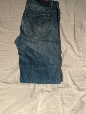 Blå raka jeans med slitningar - Säljer ett par klassiska blå jeans med raka ben och lätt slitna detaljer vid knäna. Jeansen har fem fickor och en snygg tvättad look som ger en avslappnad vibe. Perfekta för dig som gillar en tidlös och enkel stil.Pris går att diskutera.