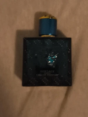 Versace Eros Eau de Parfum - Versace Eros Eau de Parfum i en mörkblå, fyrkantig glasflaska med gulddetaljer och ett turkost Medusahuvud på framsidan. Flaskan har en blå och guldfärgad kork som ger en lyxig känsla. Perfekt för dig som gillar exklusiva dofter. Helt tomm 