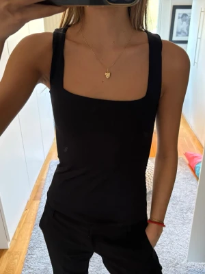 Svart linne - Svart linnetopp med breda axelband och fyrkantig ringning. 