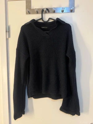 Svart stickad tröja med v-ringning - Mysig svart stickad tröja från Gina Tricot med bred v-ringning och krage. Tröjan har långa ärmar och en avslappnad passform. Perfekt för lager på lager och enkel att styla till olika outfits.