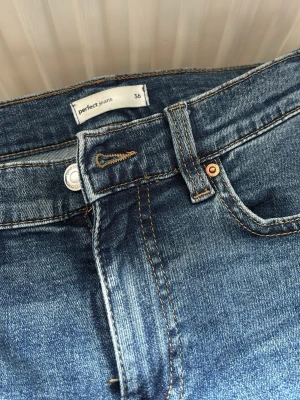 Blå bootcut jeans från Perfect Jeans - Säljer ett par klassiska blå bootcut jeans från Vero Moda i storlek 36. Jeansen har flera fickor, snygga kontrastsömmar och är tillverkade i slitstark denim. 