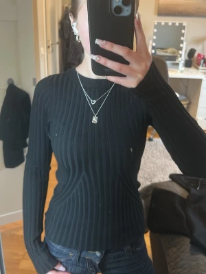 Svart ribbstickad tröja - Snygg svart ribbstickad tröja med lång ärm och rund halsringning. Tröjan har en tight passform och är perfekt att matcha med jeans eller kjol. Materialet är mjukt och stretchigt, vilket gör den bekväm att bära hela dagen. Passar både xs och s då den är stretchig och ganska lång i modellen. Säljer då jag har många liknande tröjor och tröjan är bara använd fåtal gånger 💕
