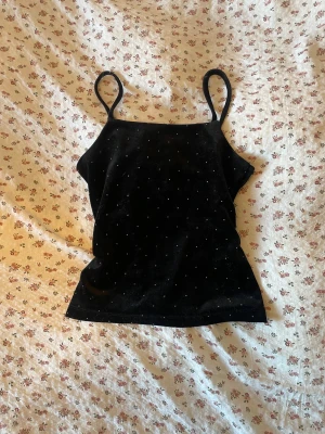 Svart glittrig linne - Snyggt svart linne med tunna axelband och små glittriga detaljer över hela tyget. Några diamanter har lossnat men det är inget man tänker på!! Kan användas både som pyjamas eller vanlig topp! 🤗🖤