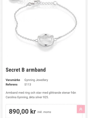 Secret B armband i silver - Snyggt armband i äkta silver 925 från Gynning Jewellery. Armbandet har en tunn kedja och ett runt hänge med en stav dekorerad med glittrande stenar. Perfekt detalj till din outfit och lätt att matcha med andra smycken.