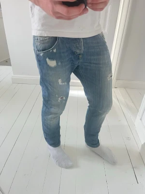 Dondup jeans  - Dondup jeans, Inga större defekter förutom att det är slitet på baksidan som har lett till håll som ni se. Modellen i bilderna är 180 cm 75 kg pch bär Storlek , har inte. Storlekar på dom men skulle säga W31, L30 , Måtten i sista bilden är A: 40 B: 92, Kom med frågor! 
