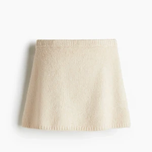 Beige stickad kortkjol och tröja SET - Supersöt beige stickad kortkjol med enkel och clean design. Kjolen har en mjuk och stretchig midja och är perfekt för dig som gillar en minimalistisk look. Det tillkommer även en matchande stickad tröja.  Tröjan är i storlek XS, kjolen är i S. Endast använd en gång vid jul. 