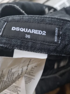 Svarta distressed jeans från Dsquared2 - Säljer ett par svarta jeans från Dsquared2 med distressed detaljer, slitningar och färgstänk för en edgy look. Jeansen har smal passform och klassisk femficksdesign. Tillverkade i bomull med lite stretch för extra komfort.