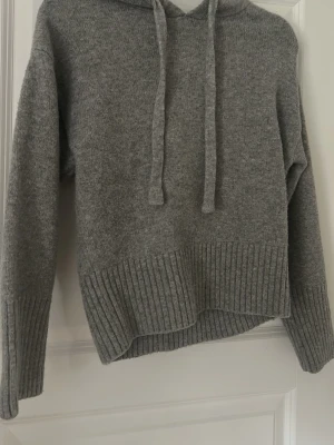 Grå hoodie från Zara med ribbade detaljer - Mysig grå hoodie från Zara med huva och dragsnören. Tröjan har ribbade muddar vid ärmslut och nederkant samt en avslappnad passform. Perfekt för chill dagar och enkel att matcha med jeans eller leggings.