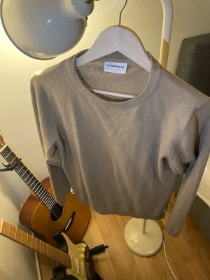 Beige stickad tröja från Lindbergh - Snygg beige stickad tröja från Lindbergh med rund halsringning och ribbade muddar. Enkel och stilren design som passar perfekt till jeans eller chinos. Långärmad modell i mjukt material.
