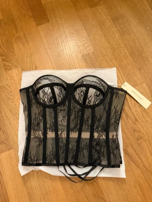 Svart spetskorsett från Perfect Corset - Så fin corset från perfect corset NY. Kuporna är vadderade och ger bra stöd, medan snörningen bak gör att du kan justera passformen. Den sitter sjukt bra och ger en väldigt fin form på kroppen! Köpt för 1100kr och säljer för 750kr!