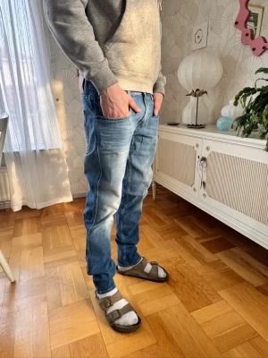 Blå jeans från Replay - Säljer ett par snygga blå jeans från Replay med klassisk femficksmodell och ljus tvätt. Jeansen har raka ben och normal midja, tillverkade i slitstark denim. Perfekta för en avslappnad och trendig stil.