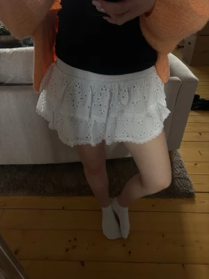 Vit volangkjol med broderade detaljer - Supersöt vit kortkjol med volanger och broderade hålmönster. Köptes förra året men användes aldrig. Lappen sitter kvar. Nypris:399kr.  Kolla gärna mina andra annonser för paketpris!🤍