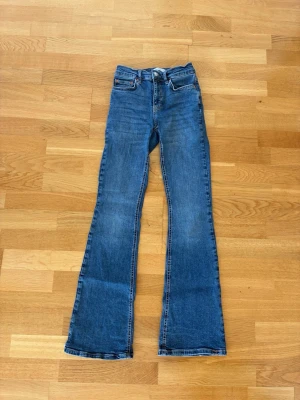 Blå bootcut jeans - Snygga blå bootcut jeans med klassisk femficksdesign. Jeansen har en lätt tvättad look och raka, utsvängda ben. 