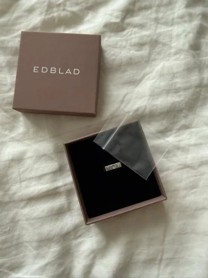 Silverring från Edblad med text - Snygg silverfärgad ring från Edblad med rektangulär platta där det står 'MOM'. Kommer i original ask och nypris 399kr.