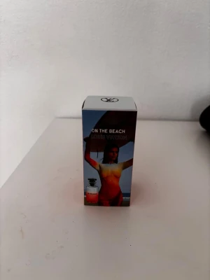 Louis Vuitton On The Beach parfym - Louis Vuitton On The Beach parfym i en snygg förpackning med färgstark design. Kartongen har en bild av en person på stranden och flaskan syns på framsidan. Märket och doftnamnet står tydligt på förpackningen i vitt och orange. Perfekt för dig som gillar exklusiva dofter.