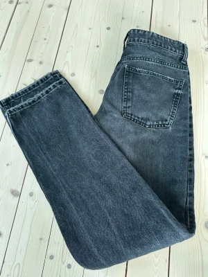 Svarta raka jeans med medelhög midja från zara - Säljer ett par svarta jeans med rak passform och medelhög midja. Jeansen har klassisk femficksdesign och stängs med knapp och dragkedja. Materialet är kraftig denim i bomull. Perfekta till en avslappnad och trendig look. Från Zara i storlek 36. Mycket fint skick! Nypris: 359kr