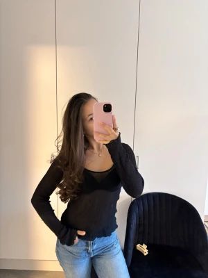 Svart ribbad långärmad topp - Snygg svart ribbad topp med lång ärm och u-ringning. Toppen är figurnära och har en lätt transparent look som ger en trendig vibe. Perfekt att styla med jeans eller kjol för en cool och enkel outfit.
