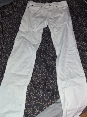 Vita slim fit jeans Calvin Klein - Säljer ett par vita slim fit jeans från Calvin Klein med stretch. Klassisk femficksmodell och snygga silverdetaljer vid knappar och nitar. Perfekta för dig som vill ha en clean och stilren look. Passar dig som är ungefär 180 cm lång.