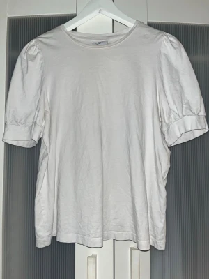 Vit topp med puffärm från Vero Moda - Säljer en vit topp från Vero Moda Aware med puffärmar och rund halsringning. Toppen är gjord i mjuk bomull och har en enkel, stilren design som passar till det mesta. Perfekt för dig som gillar en clean och trendig look.